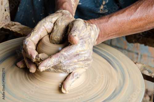 Hands of making clay pot on the pottery wheel ,select focus, close-up.