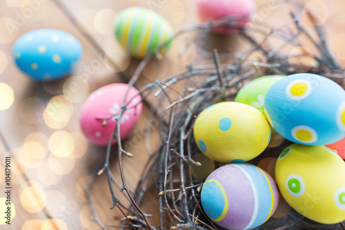 close up of colored easter eggs in nest on wood