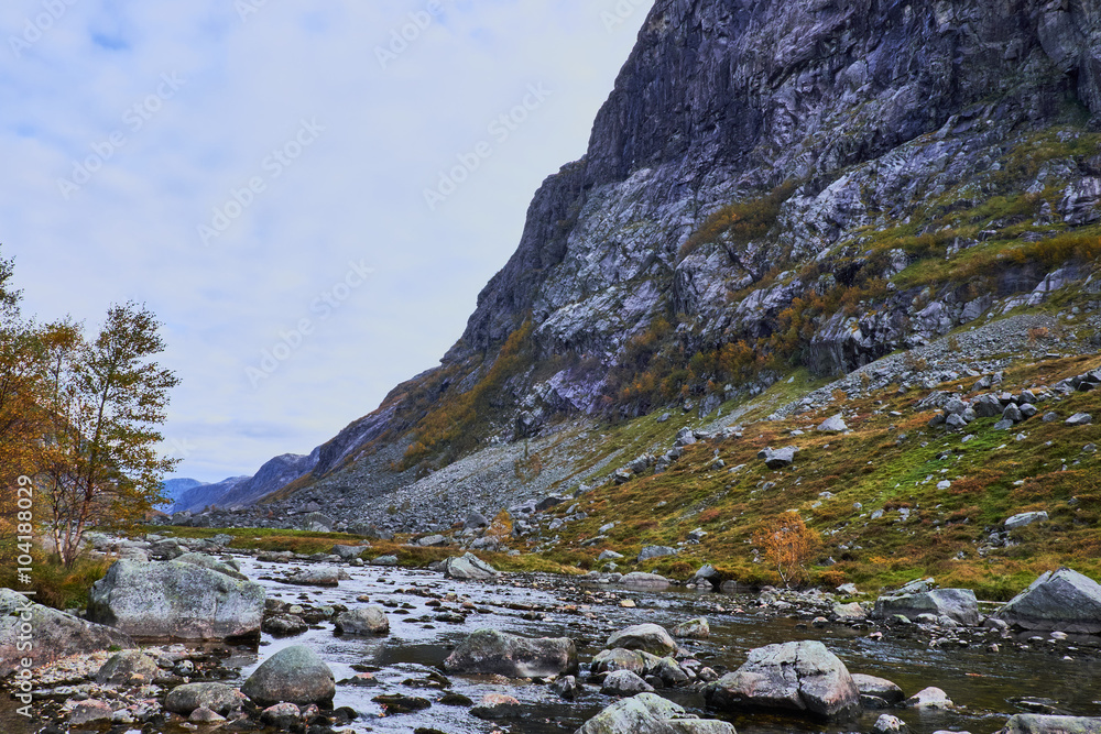 river with rock fall running at the foot of a mountain along route 45 in norway