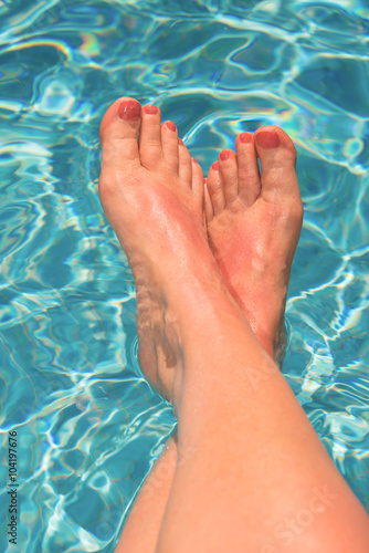 Woman feet at the swimming pool, turquoise blue water © Delphotostock