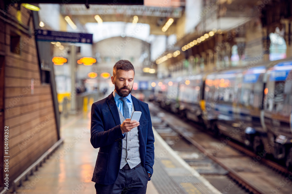 Hipster businessman with smartphone, waiting at the train platfo Hipster businessman with smartphone, waiting at the train platfo
