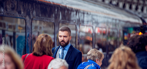 Hipster businessman walking, crowded underground platform, train