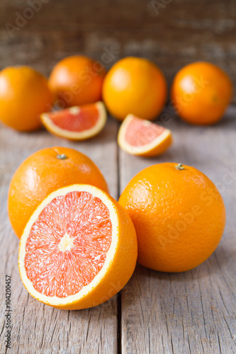 фотографія Fresh oranges with slices on wooden background.