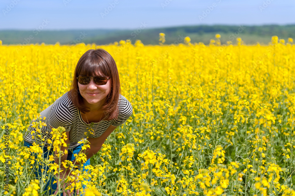 Fototapeta premium smiling girl among a field of yellow flowers