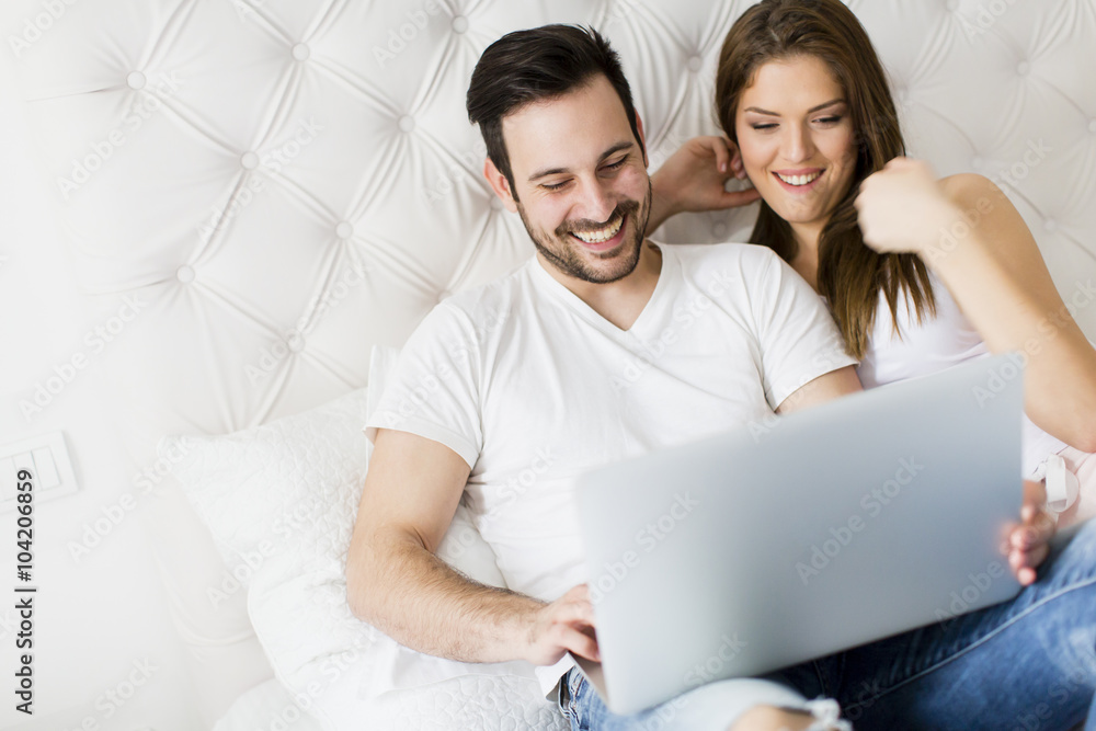 Young couple with laptop in the bed Young couple with laptop in the bed