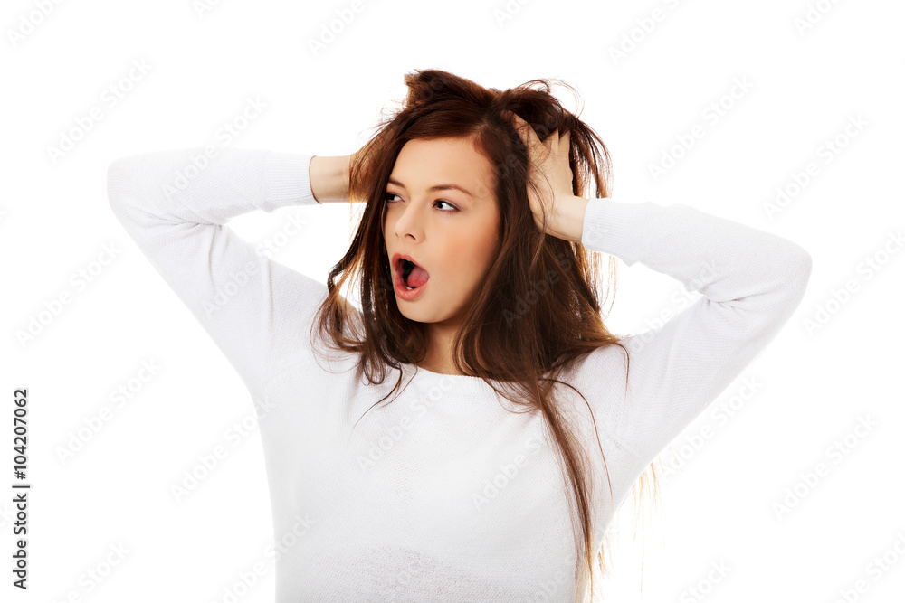 Young surprised woman holding hands inside hair Young surprised woman holding hands inside hair
