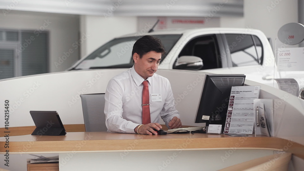 handsome car salesman talking on cell phone in showroom handsome car salesman talking on cell phone in showroom