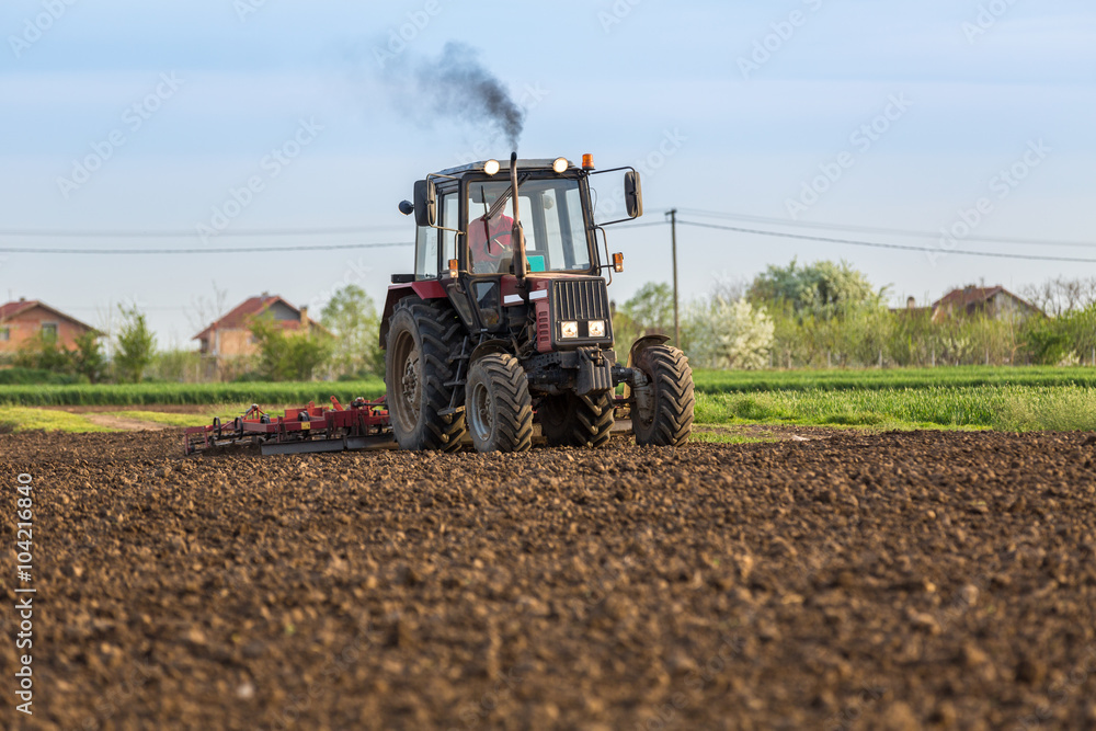 Fototapeta premium Tractor cultivating field at spring