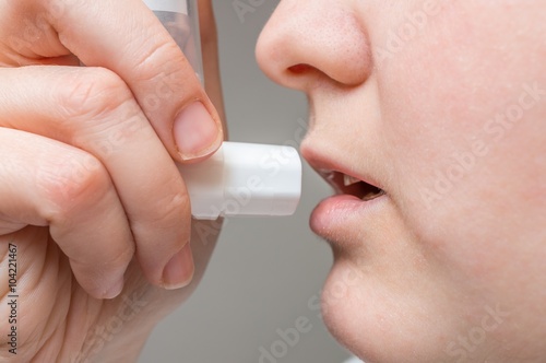 Asthmatic woman is using inhaler.