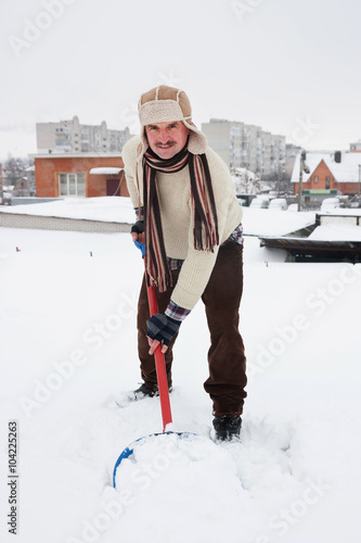 man cleans snow from roofs