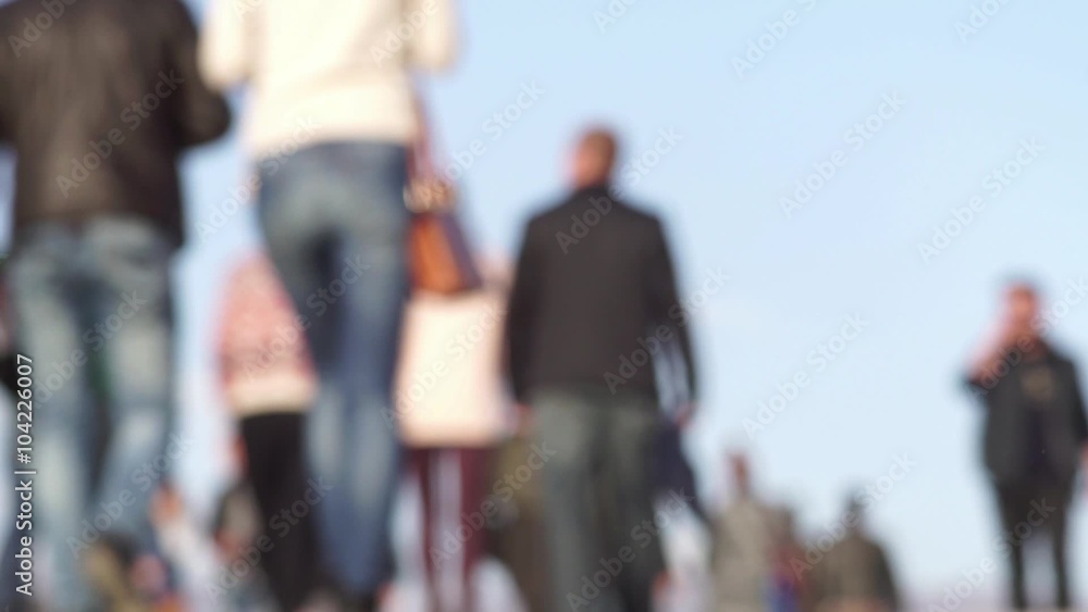 People are walking to and from the camera out of focus blurred against the sky People are walking to and from the camera out of focus blurred against the sky