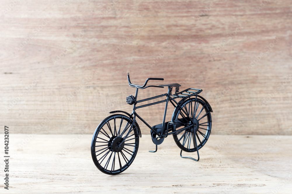 Fototapeta premium Vintage model black bicycle on old wooden table.