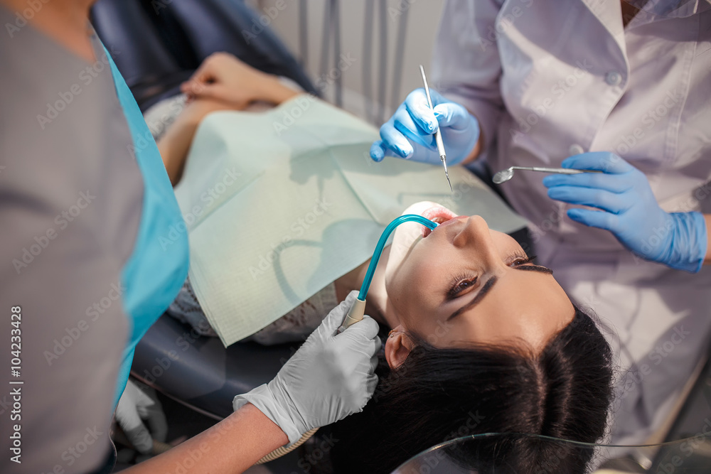 Fototapeta premium Dantist and assistant working at patients teeth. Close up portrait