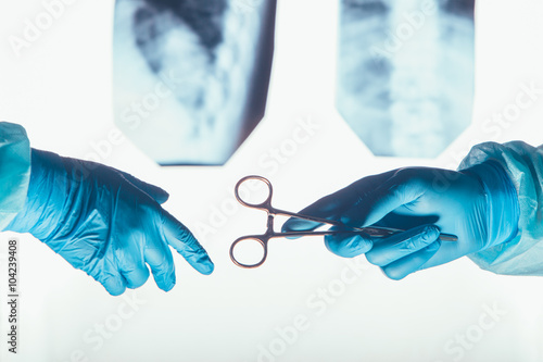 Obraz na plátně Two surgeons working and passing surgical equipment in the operating room