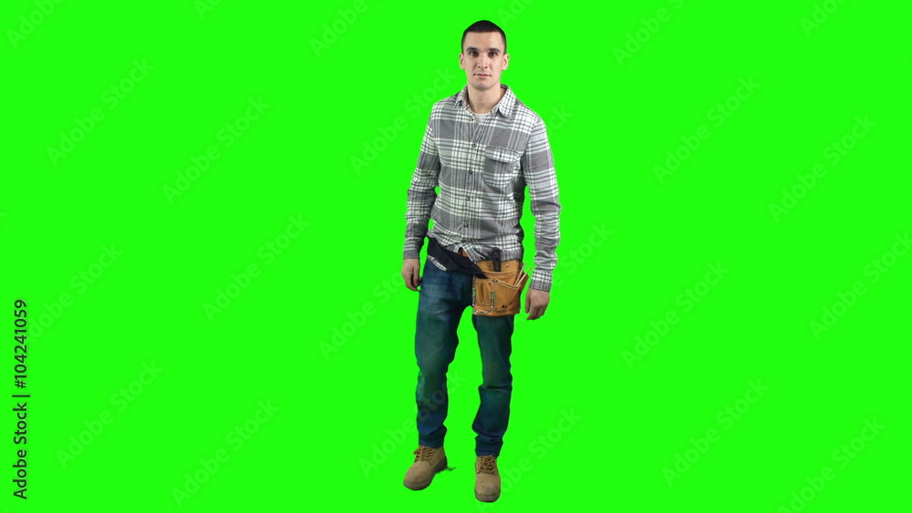 Repairman fixing his tool belt than turning and looking at camera on green screen background Repairman fixing his tool belt than turning and looking at camera on green screen background