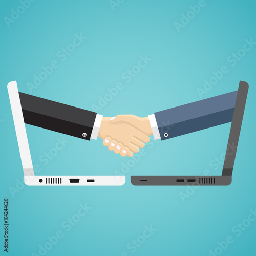 Businessmen shake hands from two computers.