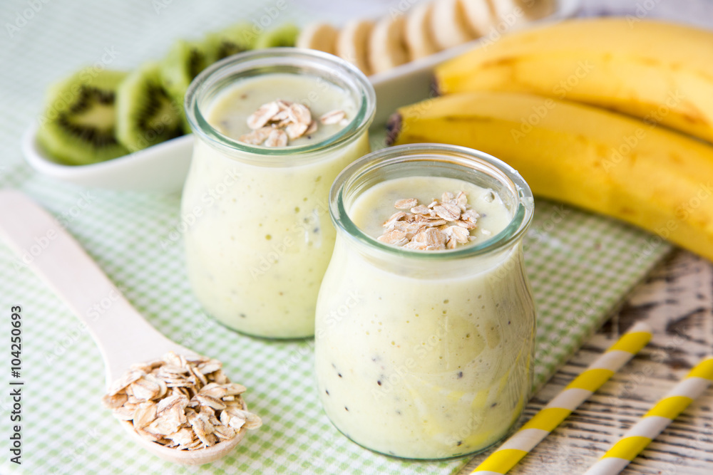 Banana smoothie with kiwi and oats on a light wooden table. Healthy food Banana smoothie with kiwi and oats on a light wooden table. Healthy food
