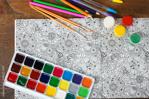 colorer - antistress with colored pencils and watercolor brushes on the wooden brown table photo