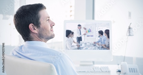 Composite image of smiling businessman sitting at his desk 