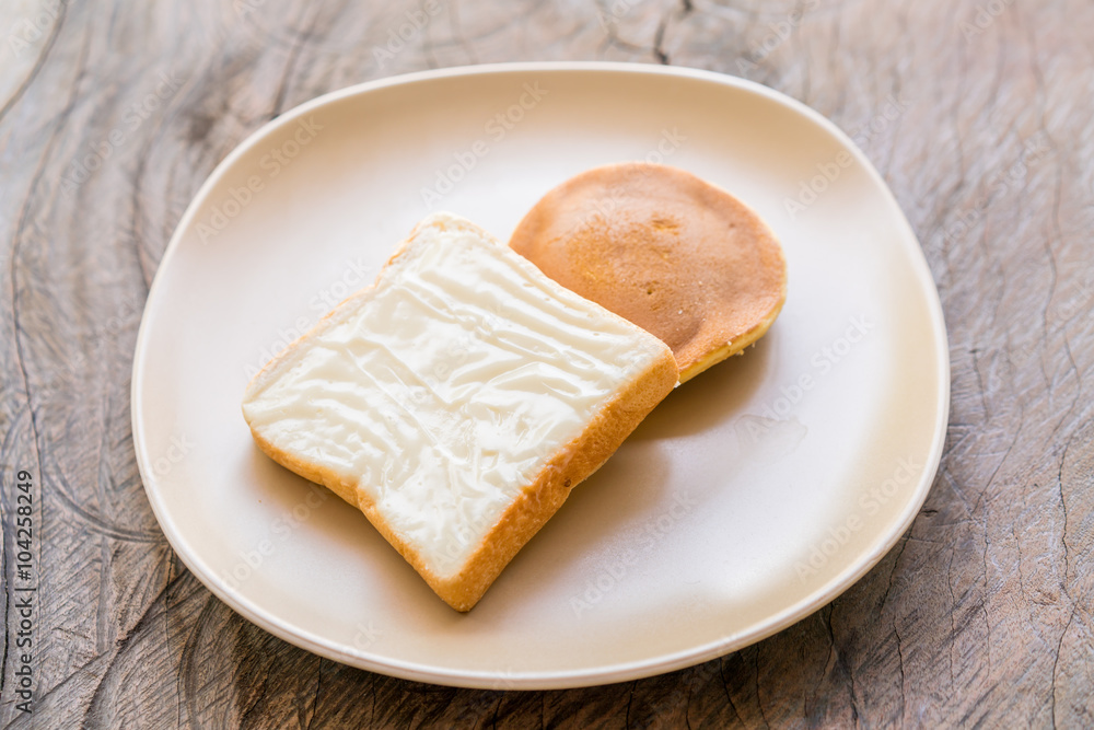 milk flavored cream spread bread slices and Dorayaki in dish on wooden texture milk flavored cream spread bread slices and Dorayaki in dish on wooden texture