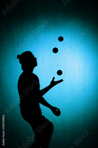 silhouette of a juggler with balls on a blue background