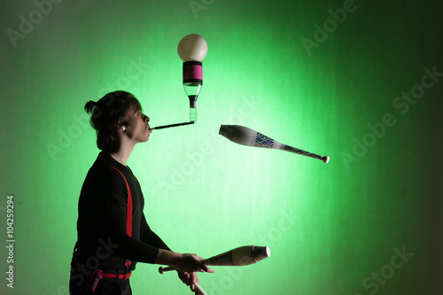 silhouette of a juggler with sticks on a green background photo