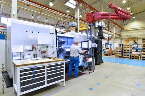 Arbeiter an einer modernen CNC Drehmaschine in einer Fabrik - bearbeitet Bauteile für die Industrie  // Worker at a modern CNC lathe in a factory © industrieblick