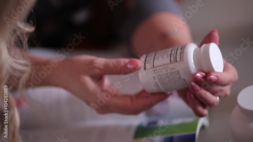 Women reading a label on a container of food supplement