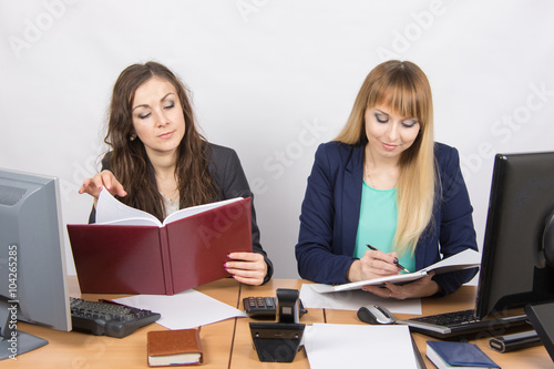 Two business women working in the office with one desk