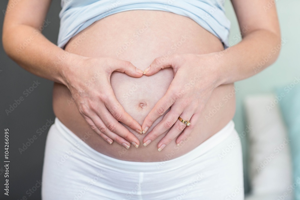 Pregnant woman doing a heart with her hand on her belly Pregnant woman doing a heart with her hand on her belly