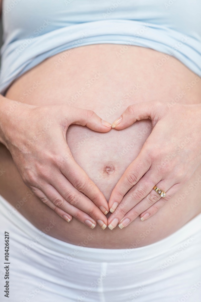 Pregnant woman doing a heart with her hand on her belly Pregnant woman doing a heart with her hand on her belly