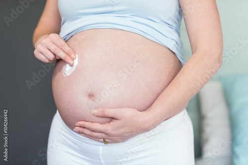 Pregnant woman applying cream on her belly © WavebreakmediaMicro