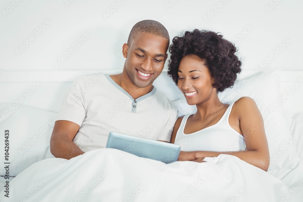 Happy couple on bed using tablet Happy couple on bed using tablet