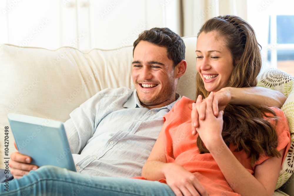 Young couple having fun while using digital tablet on sofa Young couple having fun while using digital tablet on sofa