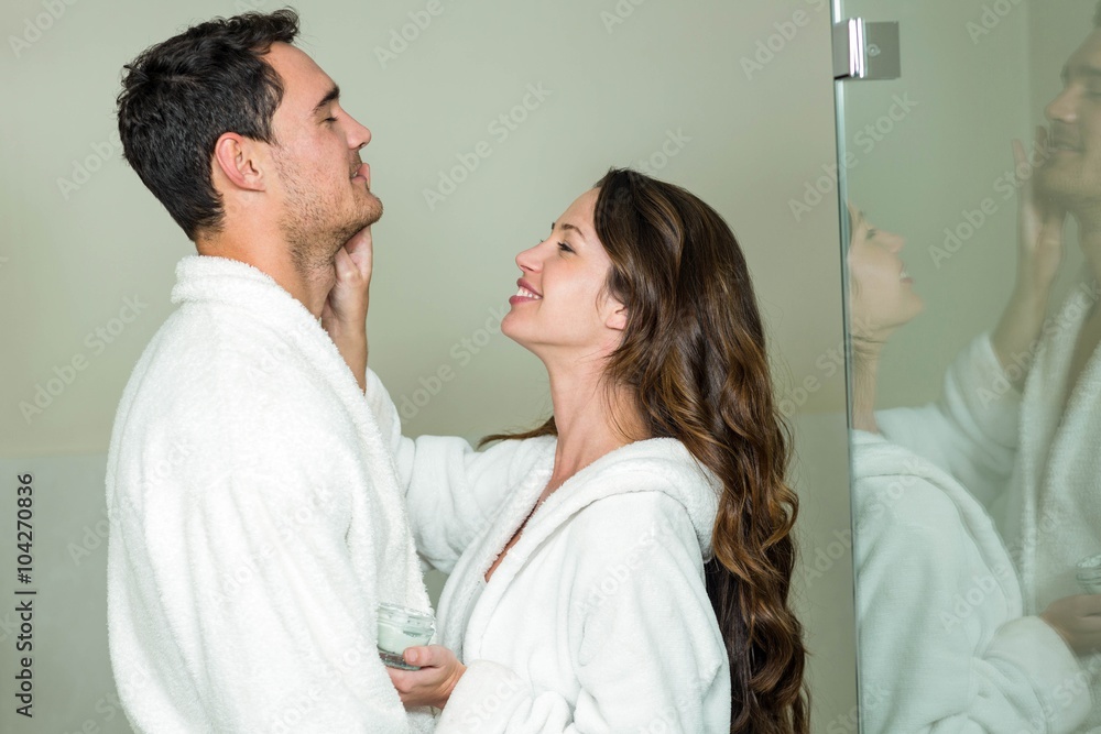 Fototapeta premium Woman applying moisturizer on man’s face