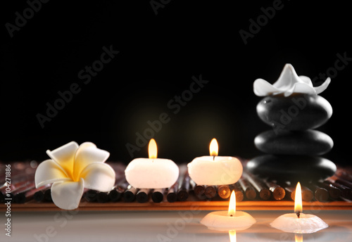 Spa still life with stones  candles and flowers in water on black background
