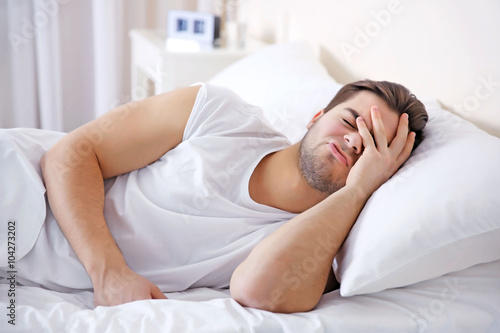 Young man lying in bed at home