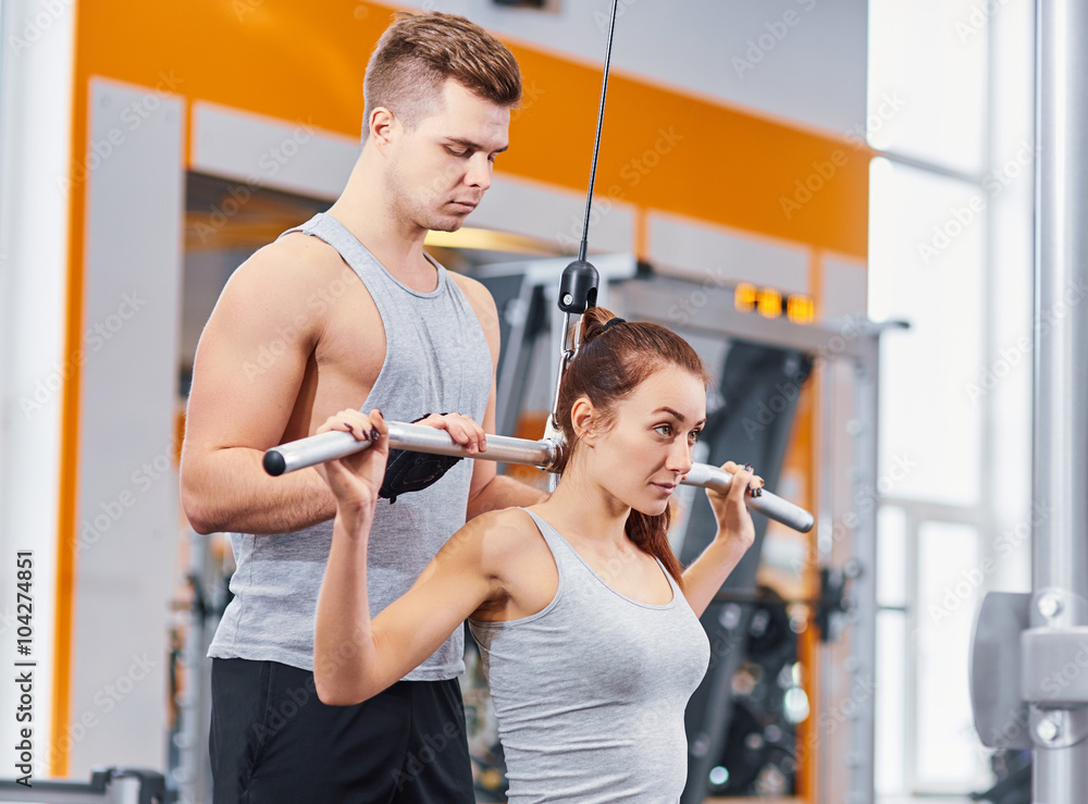 Young, beautiful girl training with the coach in the gym.