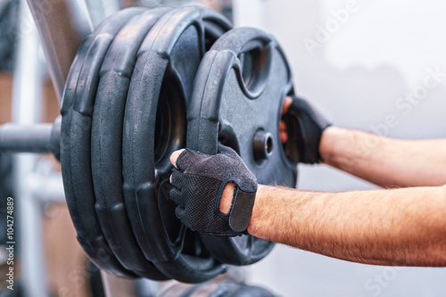 man hands holding weight plate in the gym