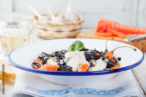 Black pasta spaghetti with cream sauce and smoked salmon Italian cuisine