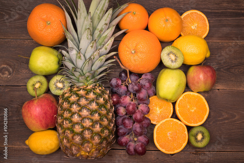 Tasty fruit background with orange, kiwi, grape, apples and lemon on the wooden table
