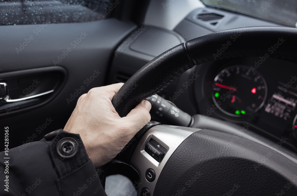 Male hand on steering wheel, car interior