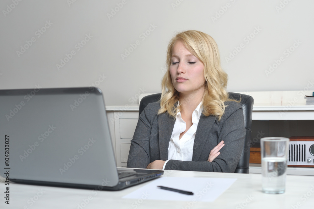 Woman with eyes closed behind her desk Woman with eyes closed behind her desk