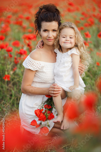 Happy mother and daughter in a field of blooming poppies