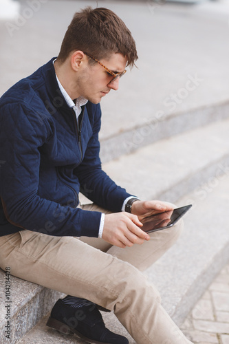 Young man with tablet computer sitting on stairs © GTeam