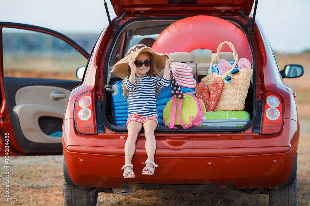 Little girl in straw hat sitting in the trunk of a car - obrazy, fototapety, plakaty 