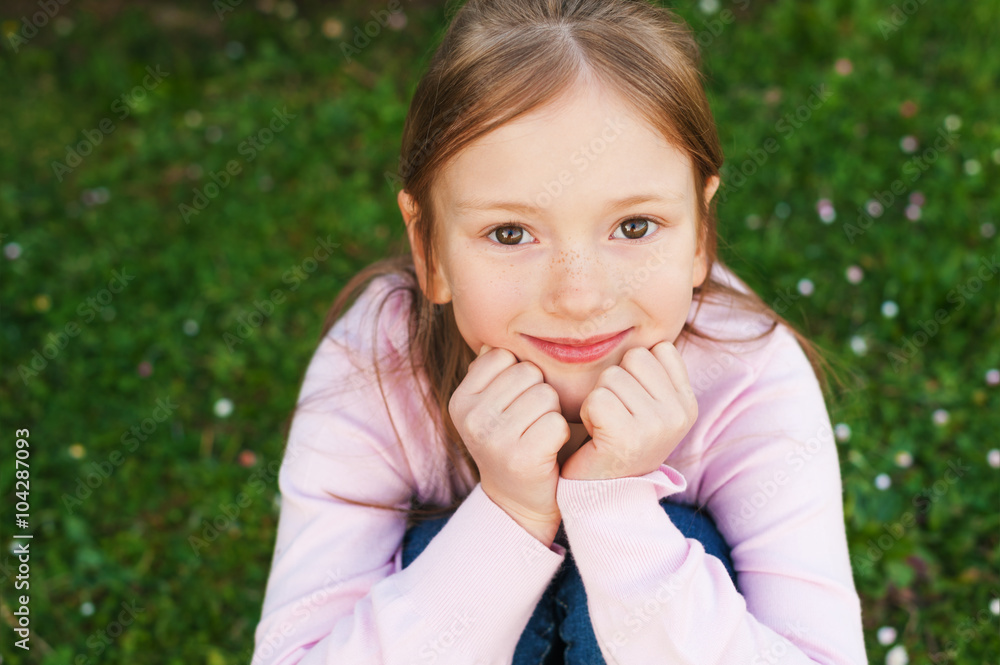 Close up portrait of adorable little girl of 6-7 years old, sitting on the ground Close up portrait of adorable little girl of 6-7 years old, sitting on the ground