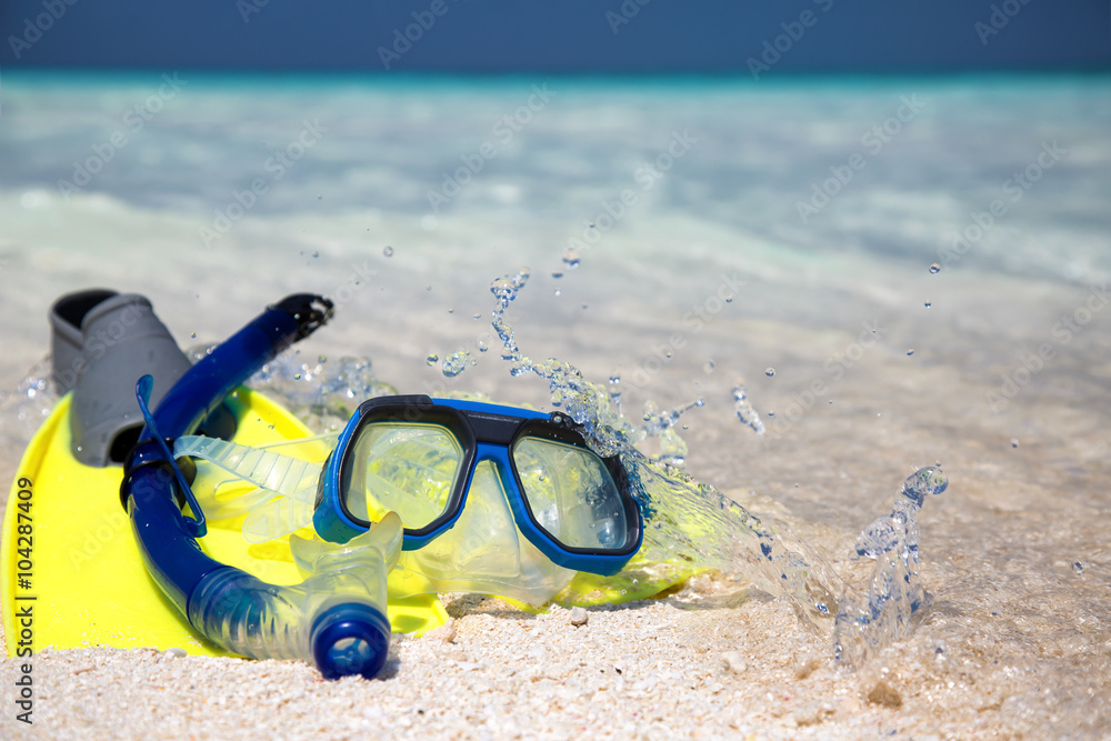 Taucherbrille und Flossen am Strand liegend