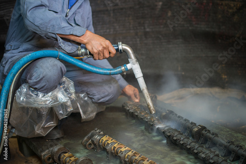 Worker is cleaning the machine equipment by using the air pressure sand / dryice blasting 