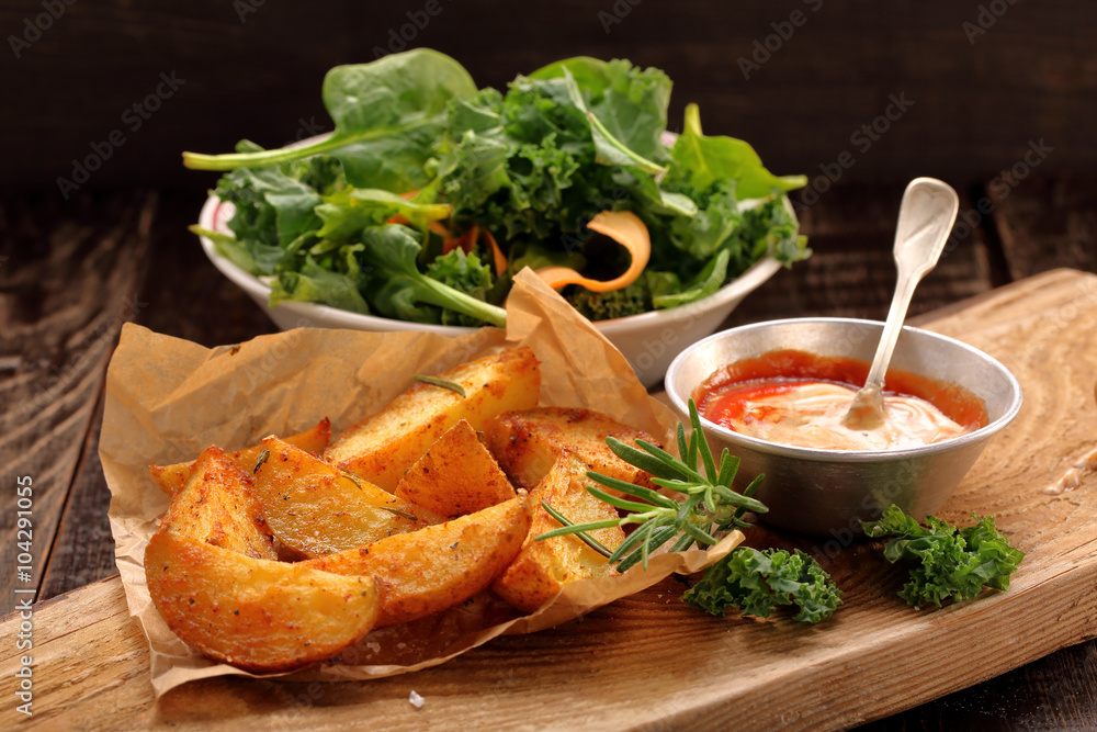 Roasted potatoes with dip and fresh salad on wooden table Roasted potatoes with dip and fresh salad on wooden table